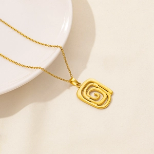 Close-up of golden geometric spiral rectangle pendant necklace on white ceramic plate