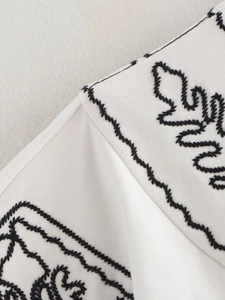 Vue détaillée d'une broderie noire sur l'encolure d'une veste blanche en coton et lin