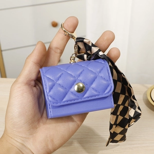 Detailed macro view of purple quilted mini coin purse with gold hardware and silk scarf