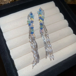 Detail of butterfly drop earrings featuring silver tassels, pearls, and colorful beads