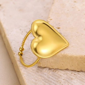 Close-up of golden heart ring with a twisted rope band on a decorative stone