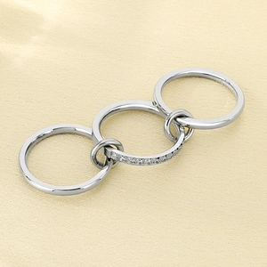 Detail of silver interlocking multi-layer rings with diamond pavé on yellow silk fabric