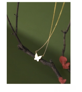 Artistic display of S925 sterling silver gold butterfly pendant on a natural wooden branch