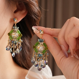 Close-up of bohemian tassel earrings with blue crystals and green beads on a model