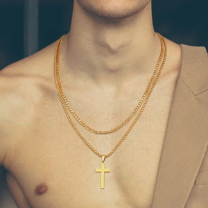 Close-up of a double-layered gold cross pendant necklace with Cuban and thin chain links