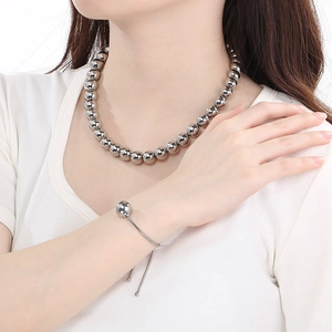 Close-up of polished stainless steel ball bead necklace and bracelet set on model