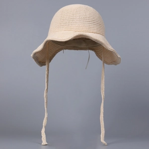 Detailed close-up of beige crochet sun hat featuring long ties and wavy scalloped brim