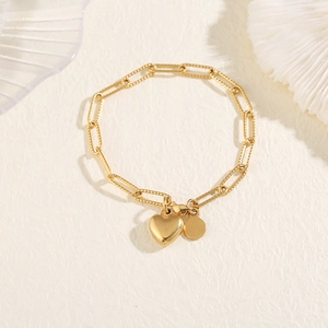 Close-up of gold stainless steel bracelet featuring textured links and heart pendant