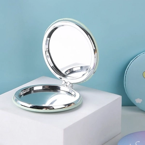 Portable light green folding makeup mirror on a white cube with 2x magnification
