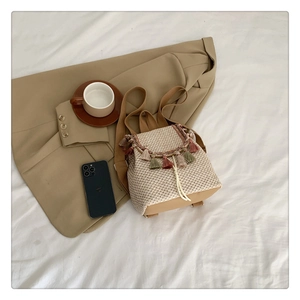 Detail of bohemian straw backpack with colorful tassels on a minimalist soft setting