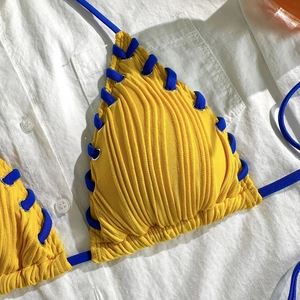 Détail du haut de bikini côtelé jaune avec liens bleus et œillets en argent