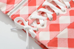 Detail of red and white checkered top with white lace-up drawstrings and metal zipper