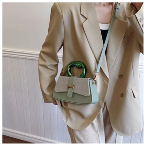 Detail view of mint green leather box bag with gold H-buckle and metallic top handle