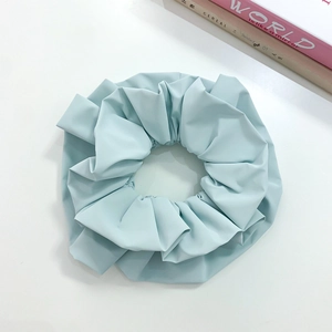 Detailed view of a large light blue pleated fabric scrunchie with soft texture