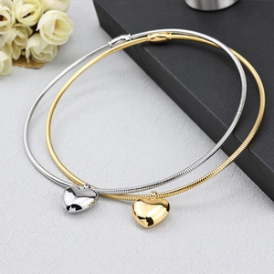 Detailed view of polished gold and silver heart pendants on classic snake chain necklaces