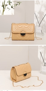 Detail of beige quilted flap bag with V-shaped stitching and metal ring closure