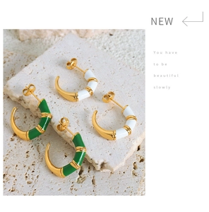 Detail of C-shaped enamel bamboo hoop earrings in green and white on stone slab