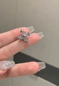 Close-up of silver cross star ear cuff with sparkling pavé zircons held by hand