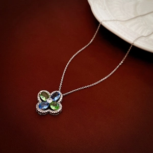 Macro shot of silver necklace with blue and green gemstone clover pendant and micro-diamonds