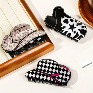 Three western cowboy style claw clips with boot and hat patterns on a wooden jewelry stand