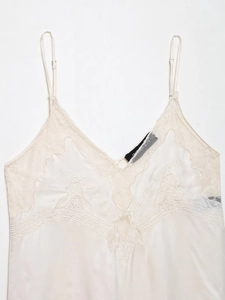 Detailaufnahme des elfenbeinfarbenen Satin-Tops mit feiner Stickerei-Spitze und V-Ausschnitt