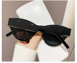 Detail of glossy black cat-eye sunglasses with thick frames and dark UV-protective lenses