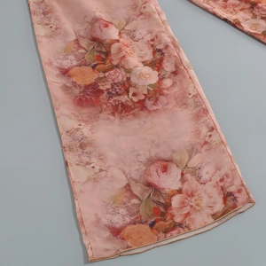 Detailed view of floral print chiffon fabric on pink wide-leg trousers for women