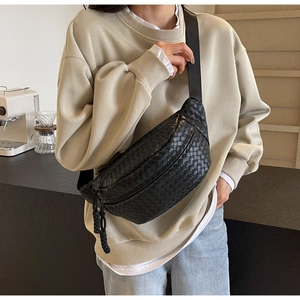 Close-up of black woven leather chest bag detail showing texture and wide strap