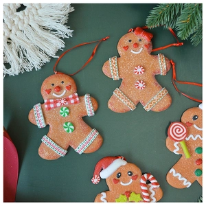 Detail of gingerbread man Christmas tree ornaments with red ribbons on green pine branches
