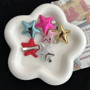 Set of colorful Y2K star hair clips in blue, pink, and metallic shades on white tray