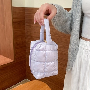 Close-up of a light purple quilted puffer handbag with diamond patterns and matching handle