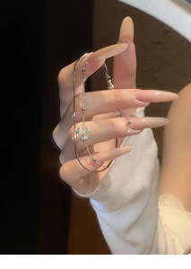 Close-up of a silver flower bracelet featuring sparkling crystals held by a model