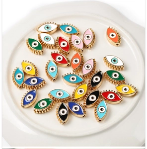 Detailed view of colorful evil eye enamel charms in a white ceramic tray for DIY jewelry