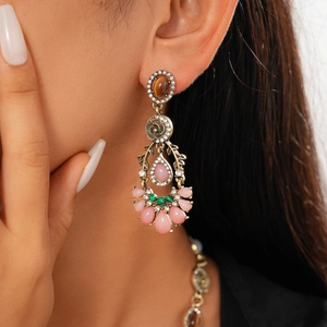 Close-up of vintage bronze earrings with amber gems and pink teardrop beads