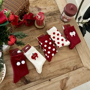 Five pairs of festive Christmas thick knit socks with red patterns on a wooden desk
