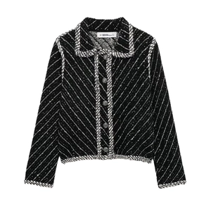 Detail of tweed knit jacket with white braided trim, lapel collar, and silver buttons