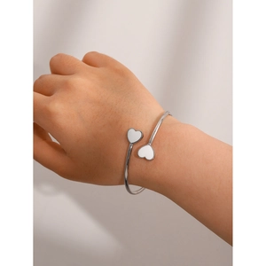 Close-up of a silver stainless steel double heart open bangle worn on a woman's wrist