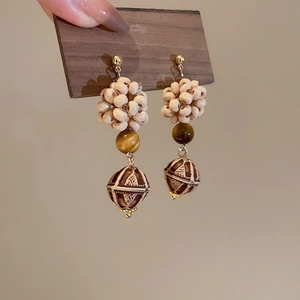 Macro shot of ethnic boho drop earrings featuring wooden beads and tiger eye stones