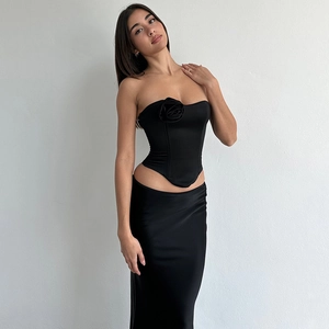 Dettaglio di un top a corsetto nero senza spalline con fiore 3D e gonna lunga abbinata