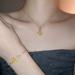 Close-up of 18k gold plated necklace and bracelet set with yellow floral pendants