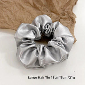 Detail of a 13cm large silver PU leather scrunchie with metallic texture and glossy finish