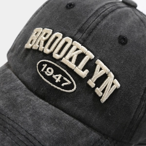 Macro shot of 3D Brooklyn 1947 embroidery on washed dark grey cotton baseball cap