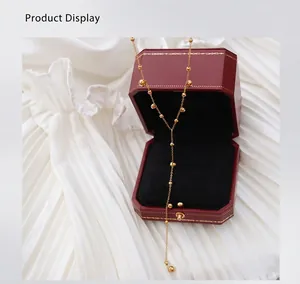 Detailed view of a gold beaded Y-shaped tassel necklace inside a red octagonal jewelry box