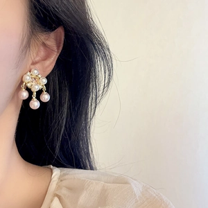 Elegant pearl drop earrings with floral crystal base and gold plating on female model