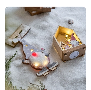 Close-up of lighted Christmas gnome and wooden snow house with LED silhouette decorations