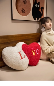 Detail of red and white heart plush pillows with embroidered Love lettering texture