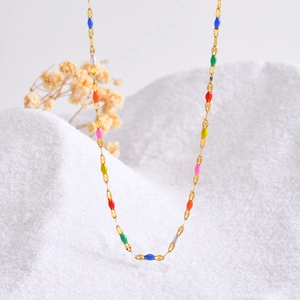 Gold stainless steel necklace with vibrant colorful beads on white textured background
