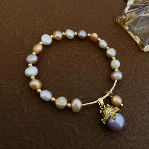 Macro view of multi-color baroque pearls with golden spacers and crystal pendant detail