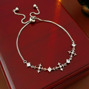 Macro detail of silver bolo bracelet featuring zircon stones and cross charms on wood