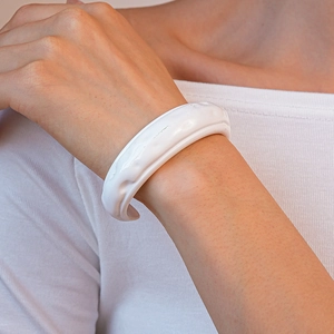 Primo piano di un bracciale a polsino in acrilico bianco plissettato indossato da un modello